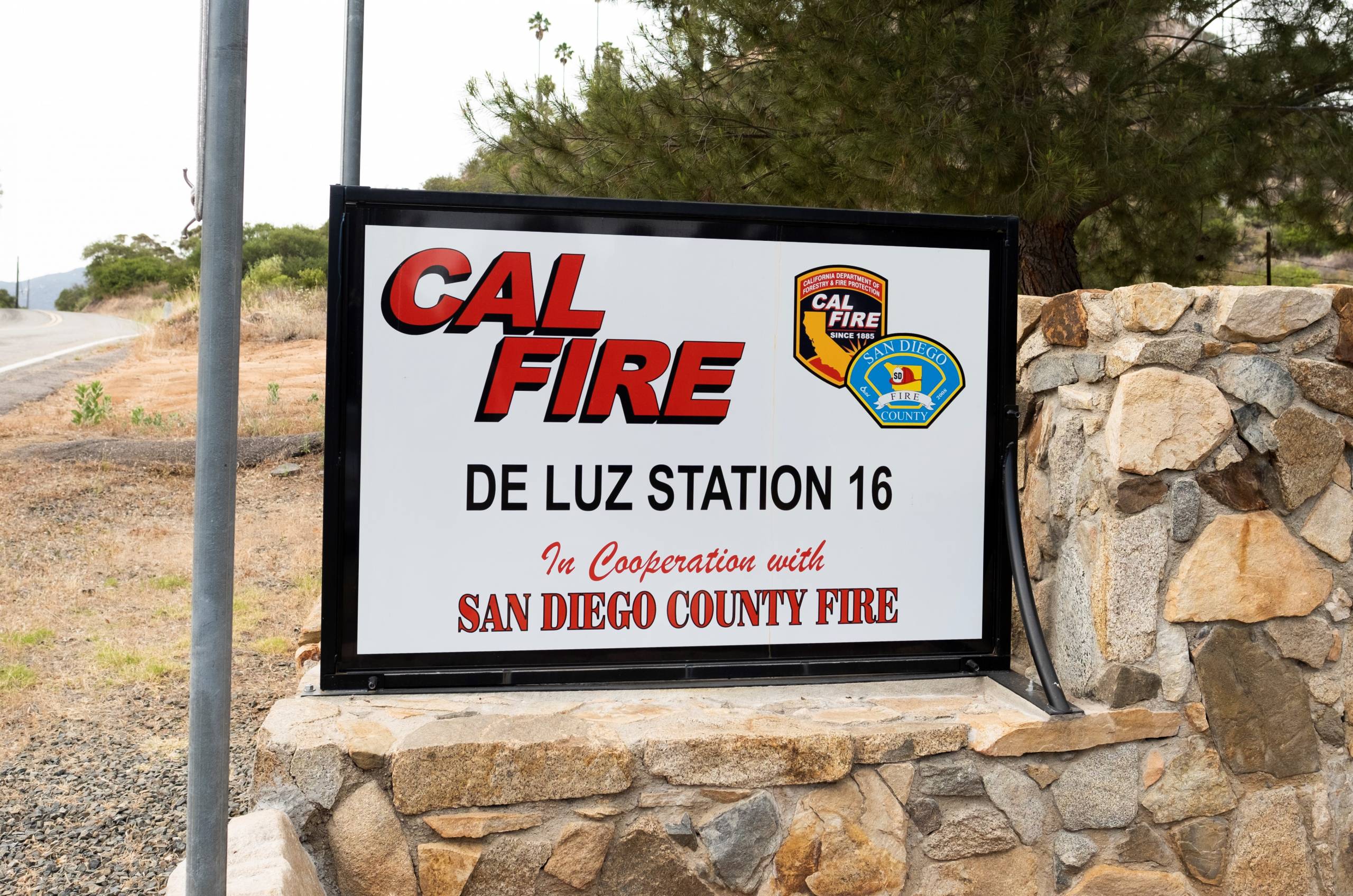A sign that reads, 'Cal Fire De Luz Station 16' next to a country road.