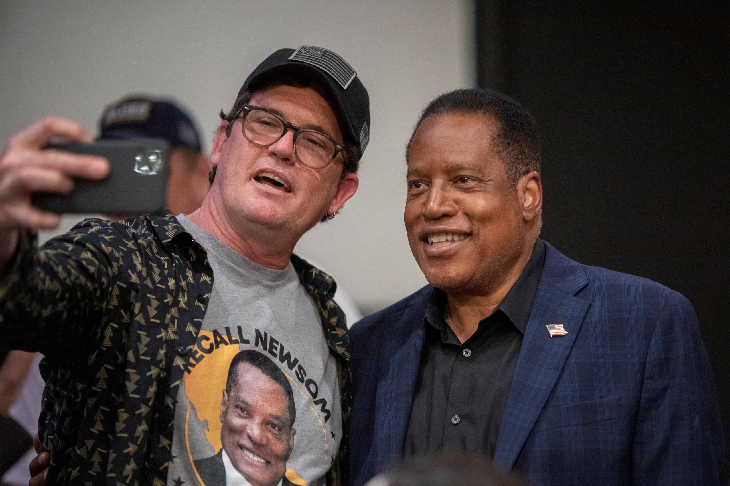 A man wearing a "Recall Newsom" T-shirt takes a selfie with Larry Elder.