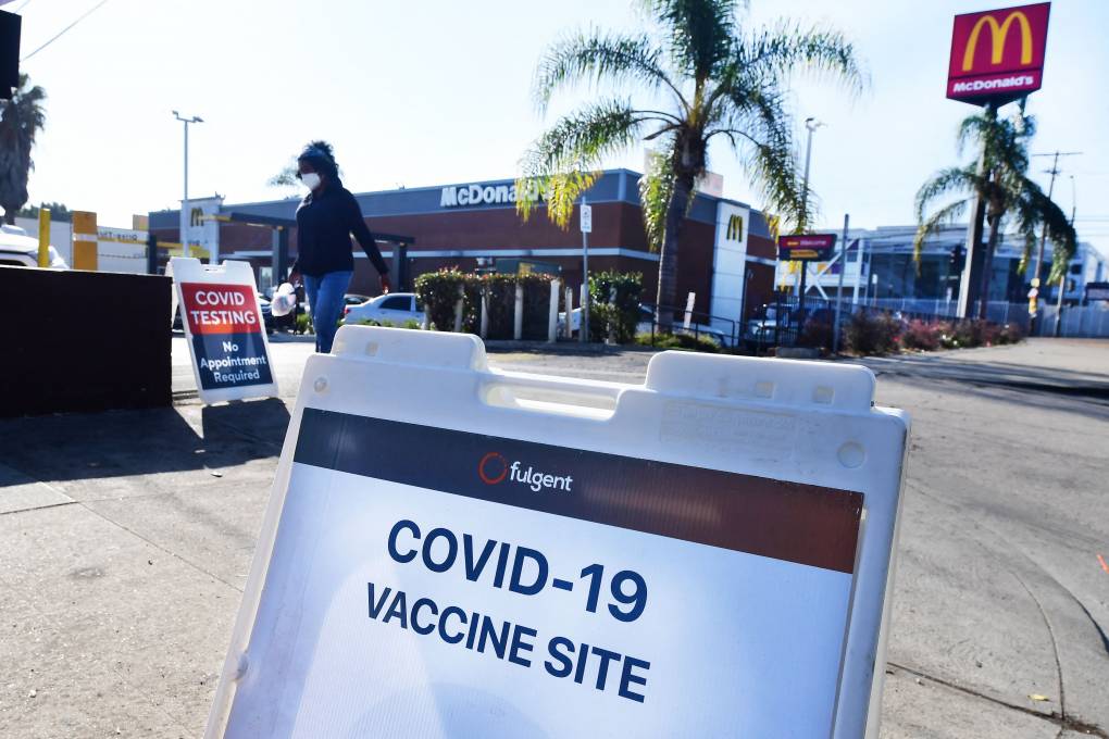 A sign in the foreground reads, "COVID-19 Vaccine Site," beyond a McDonald's restaurant.