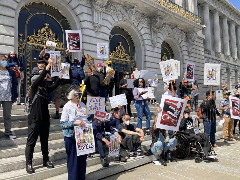 Advocates with posters demonstrate outside San Francisco City Hall.