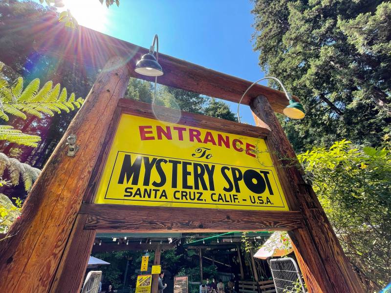 A large yellow-and-black sign reads "Welcome to Mystery Spot, Santa Cruz, California U.S.A."