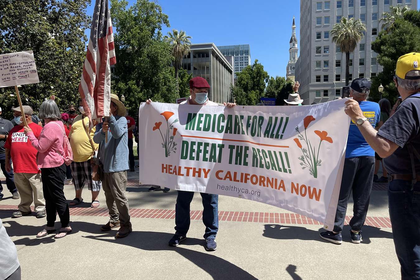 Protesters hold up a sign that reads, "Medicare for All! Defeat the Recall! Healthy California Now."