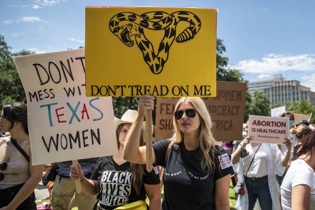 A protester holds a sign saying "Don't tread on me," with a snake forming the shape of a female reproductive system.