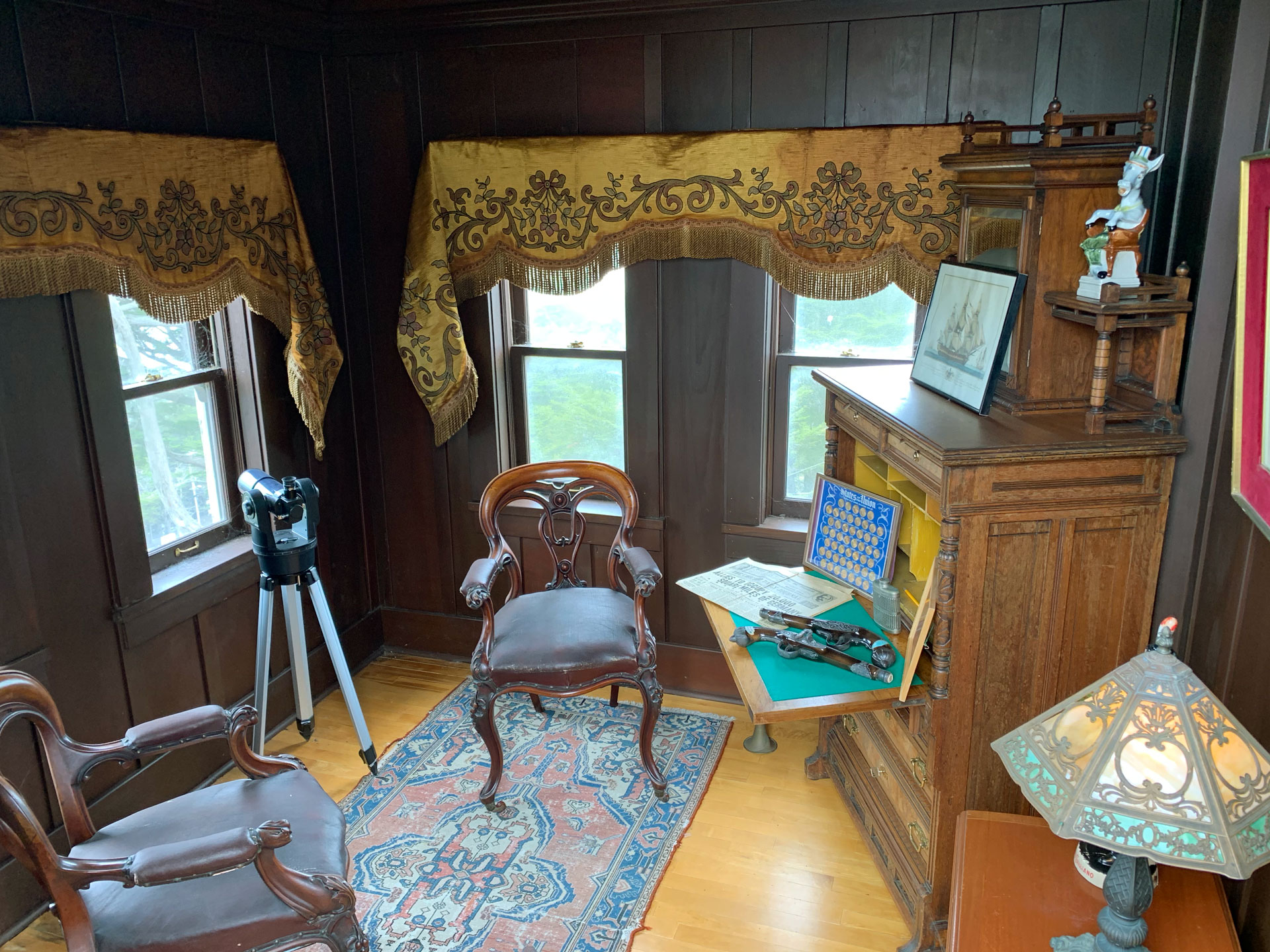 A small room with two chairs, spyglass and desk.