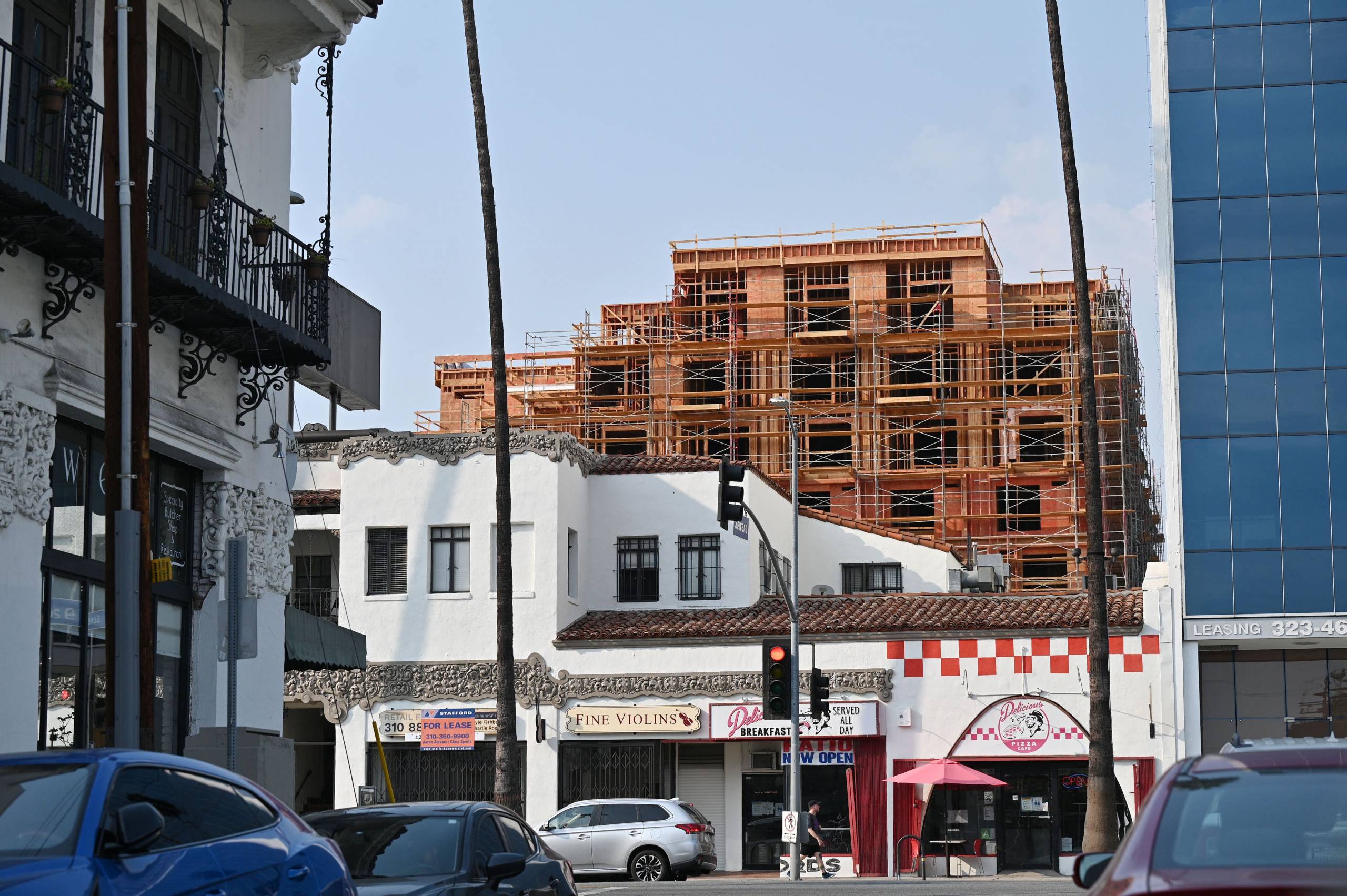 A wooden facade with scaffolding towers over the older, more residential buildings.