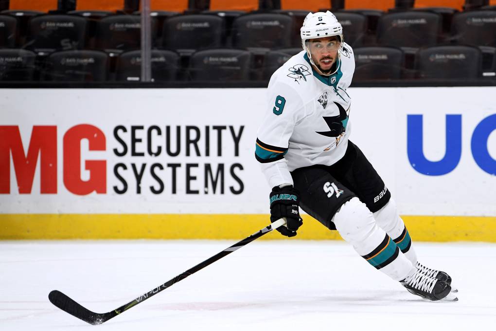 Evander Kane extends his hockey stick as he skillfully skates on the ice.