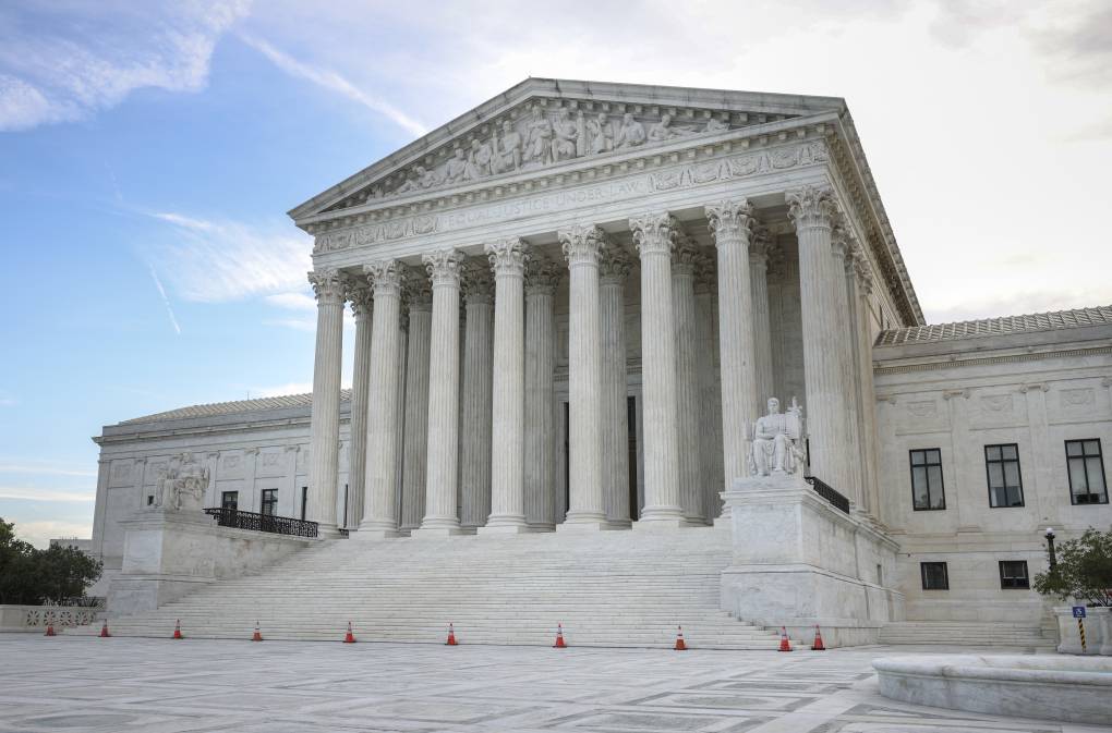 The Supreme Court building, modeled on a classical Roman temple made of white marble with massive pillars and steps all around, is empty outside, with some cones blocking off the main entrance.