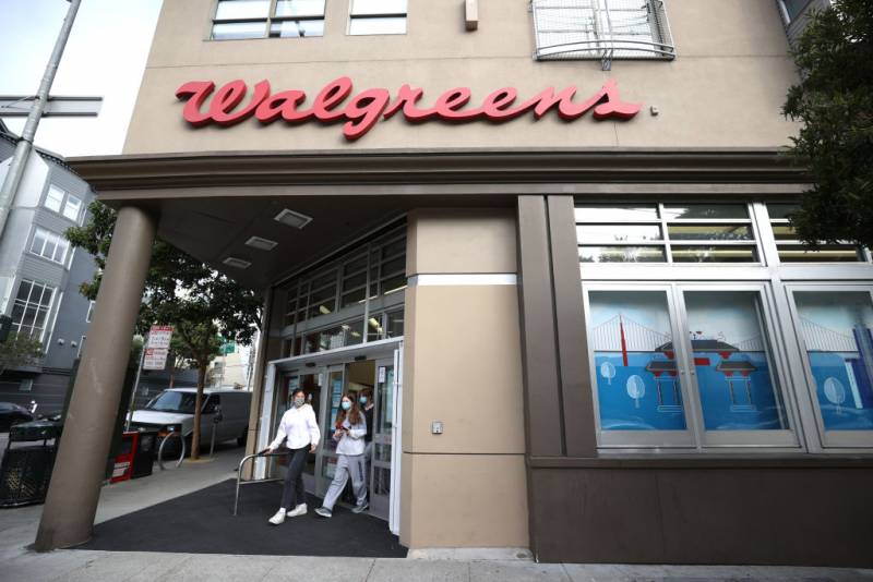 People walk out of a Walgreens store.