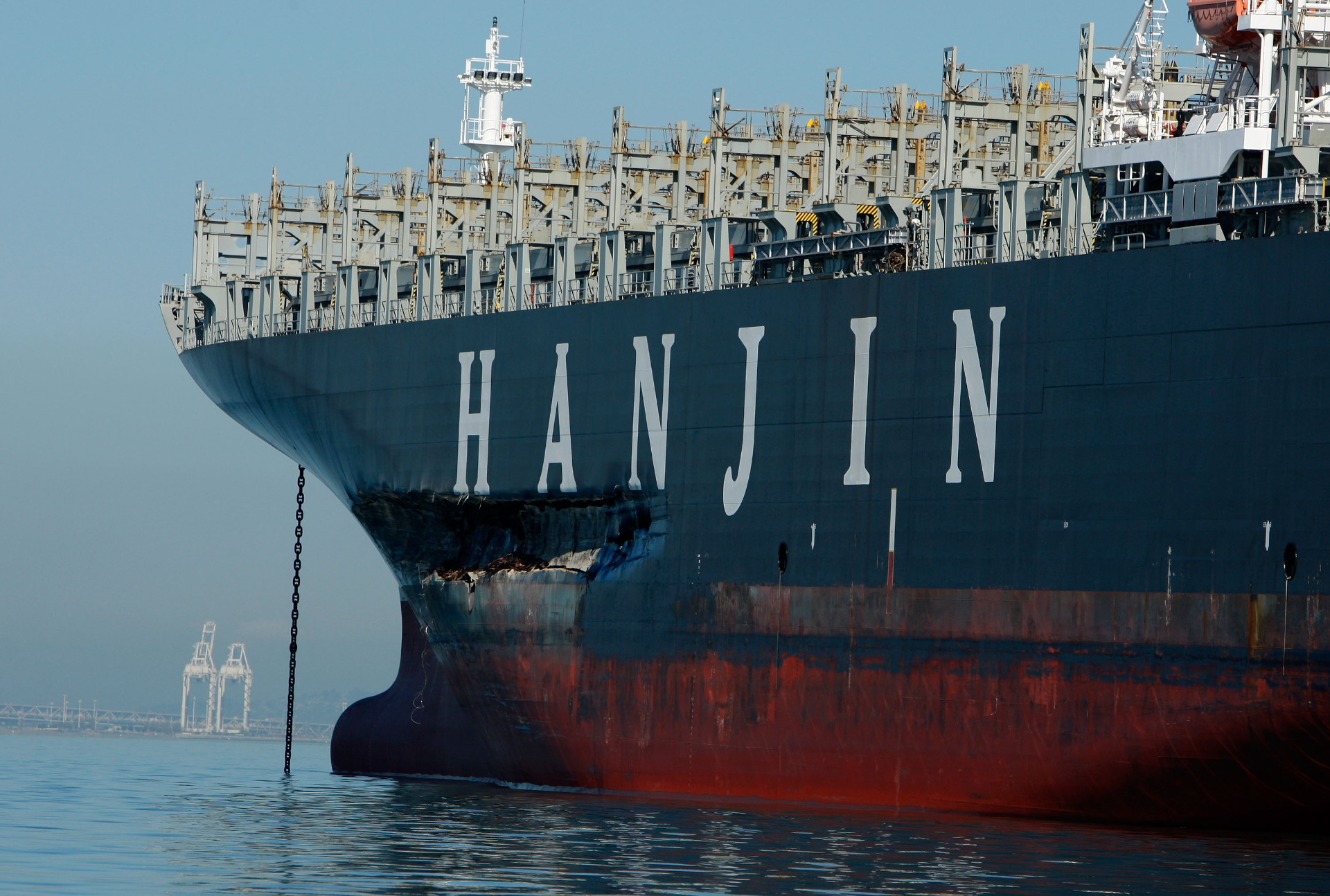 A large oil cargo ship sits in water with obvious damage to its hull.