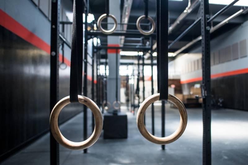 An image shows crossfit rings hanging with an empty gym in the background.