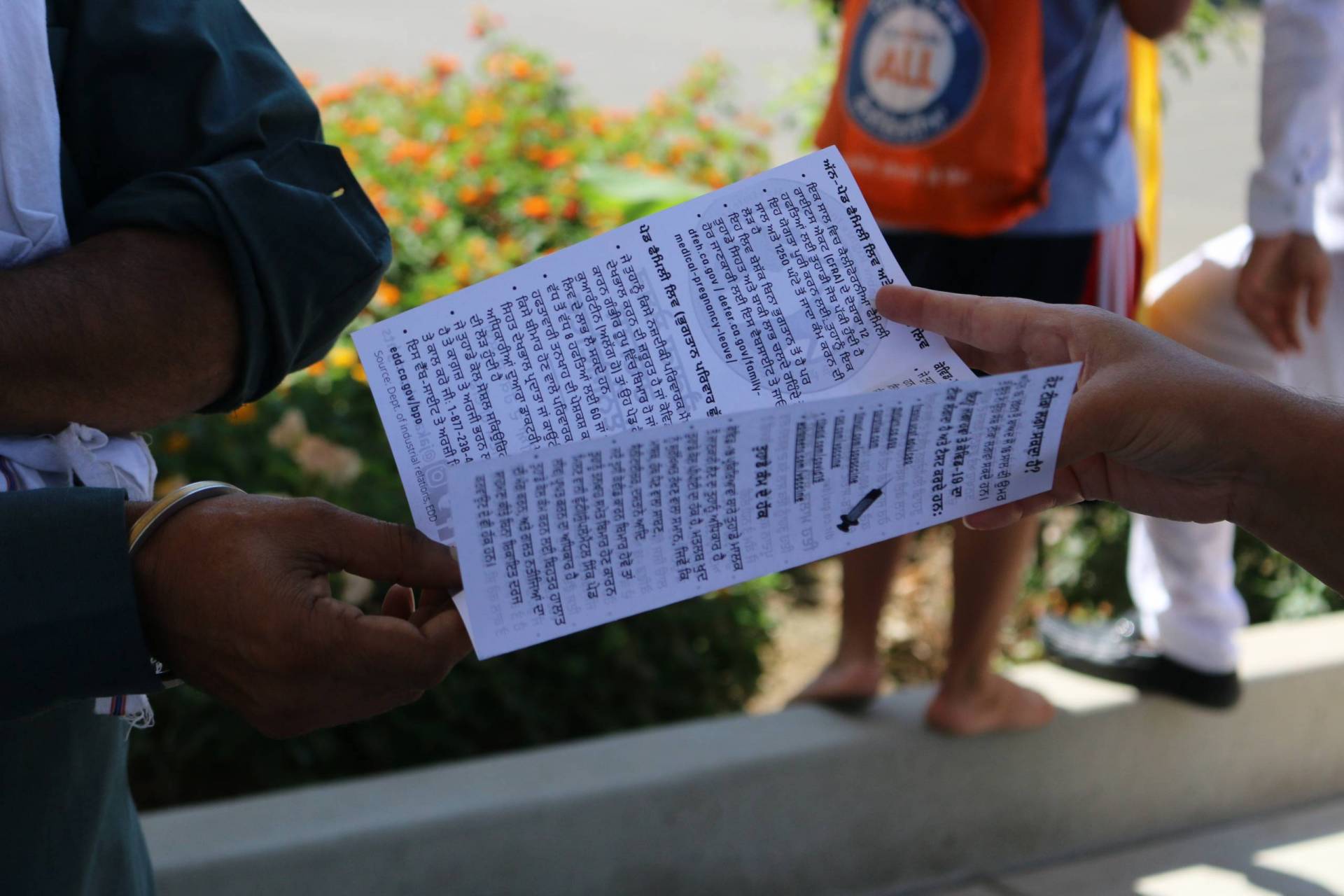 A hand holds a pamphlet open as a second hand holds it by the other end.