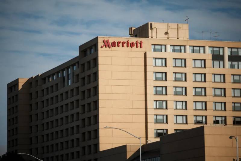 A multistory beige, windowed building with the one-story, red letters spelling "Marriott" toward the top.