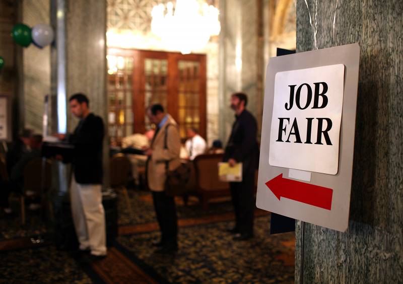 A sign saying "Job Fair" with a big red arrow points to a line of people.