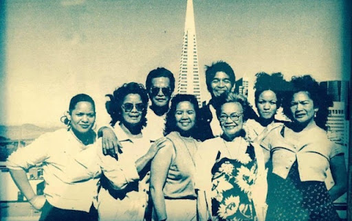 A family photo of eight people in front of the TransAmerica Pyramid building in San Francisco.