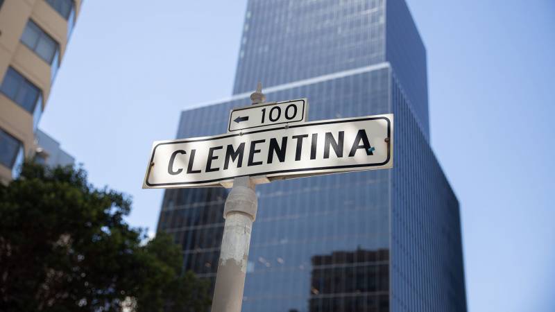 Street sign reads Clementina with tall glass building in background.