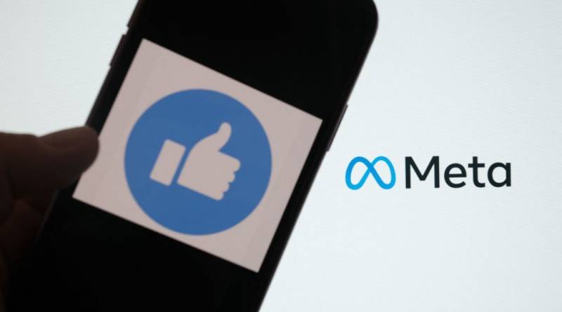 The Facebook "thumb's up" logo on a smartphone, with the "Meta" logo in the background.