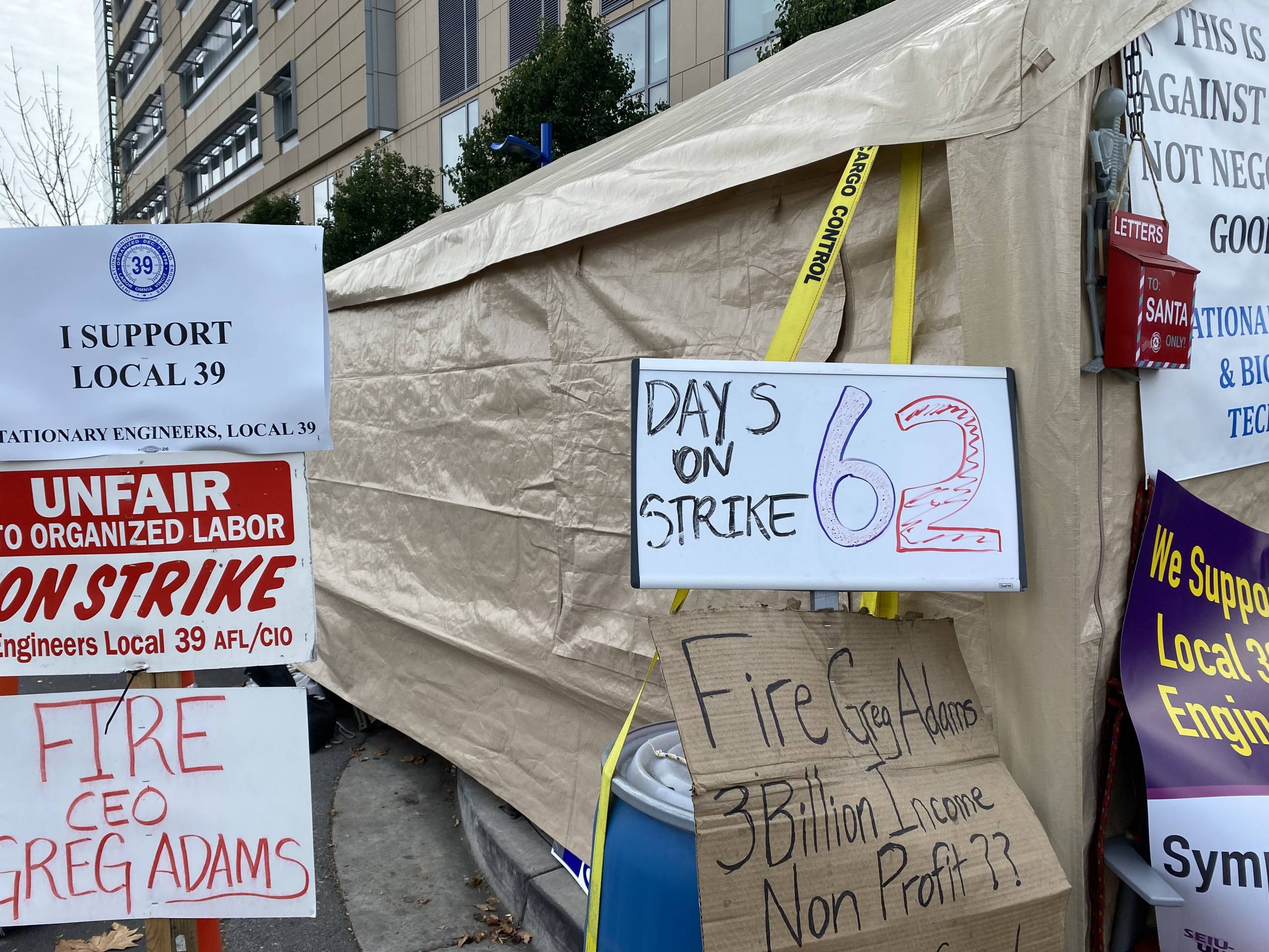Tent with sign reading "Days on Strike: 62" and "Fire CEO Greg Adams" and "I Support Local 39," the union representing Kaiser's stationery engineers.
