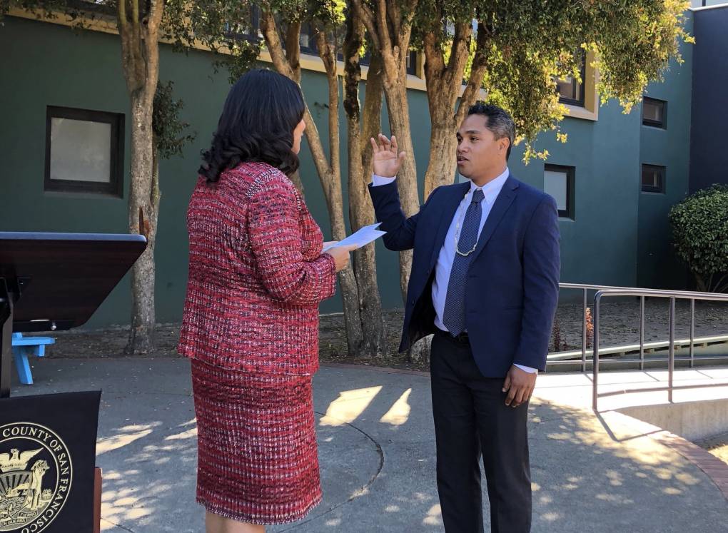 SF Mayor London Breed faces a man in a suit holding up his right hand.