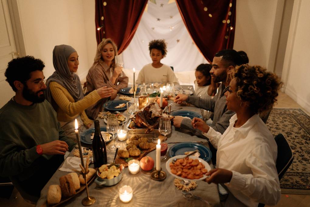 A gathering of friends around a candlelit table with turkey in the middle of the feast.