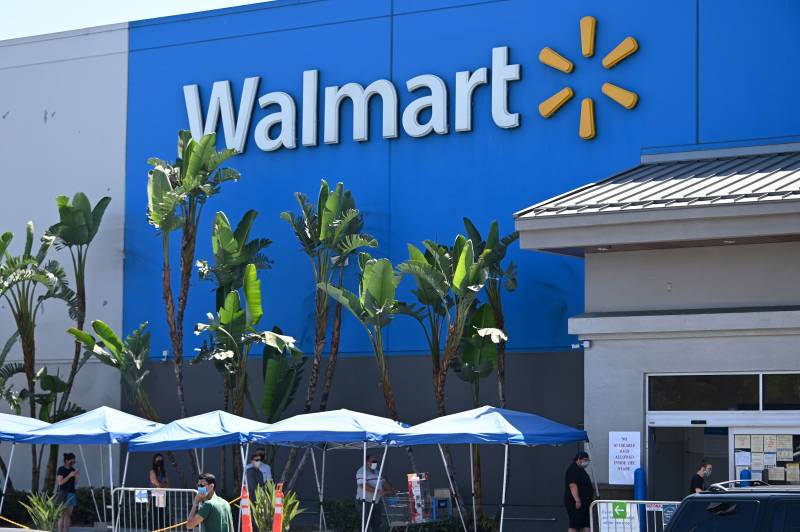 In front of the large Walmart store there are many palm trees and tents.