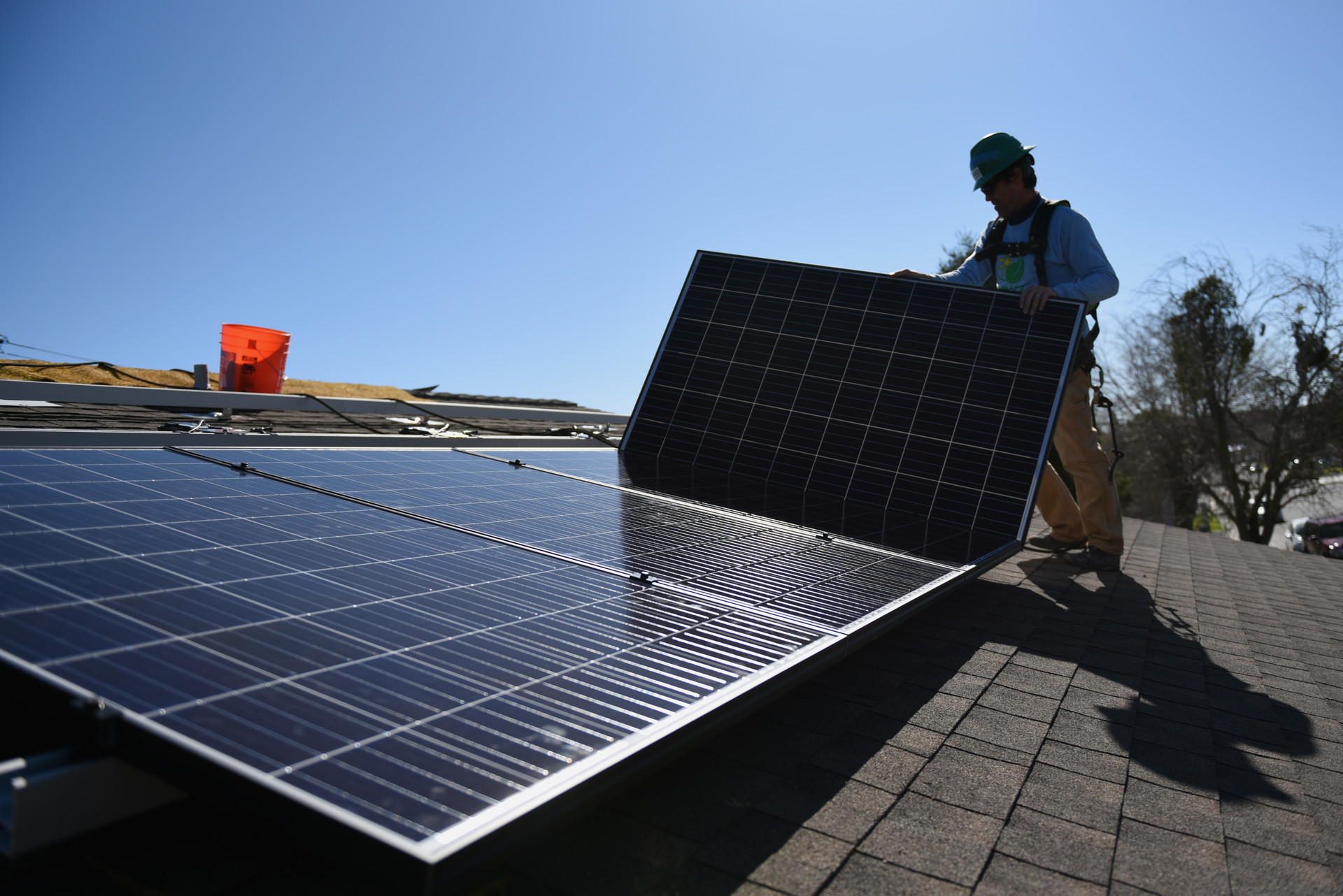 man lifts panel onto existing large rooftop solar panel