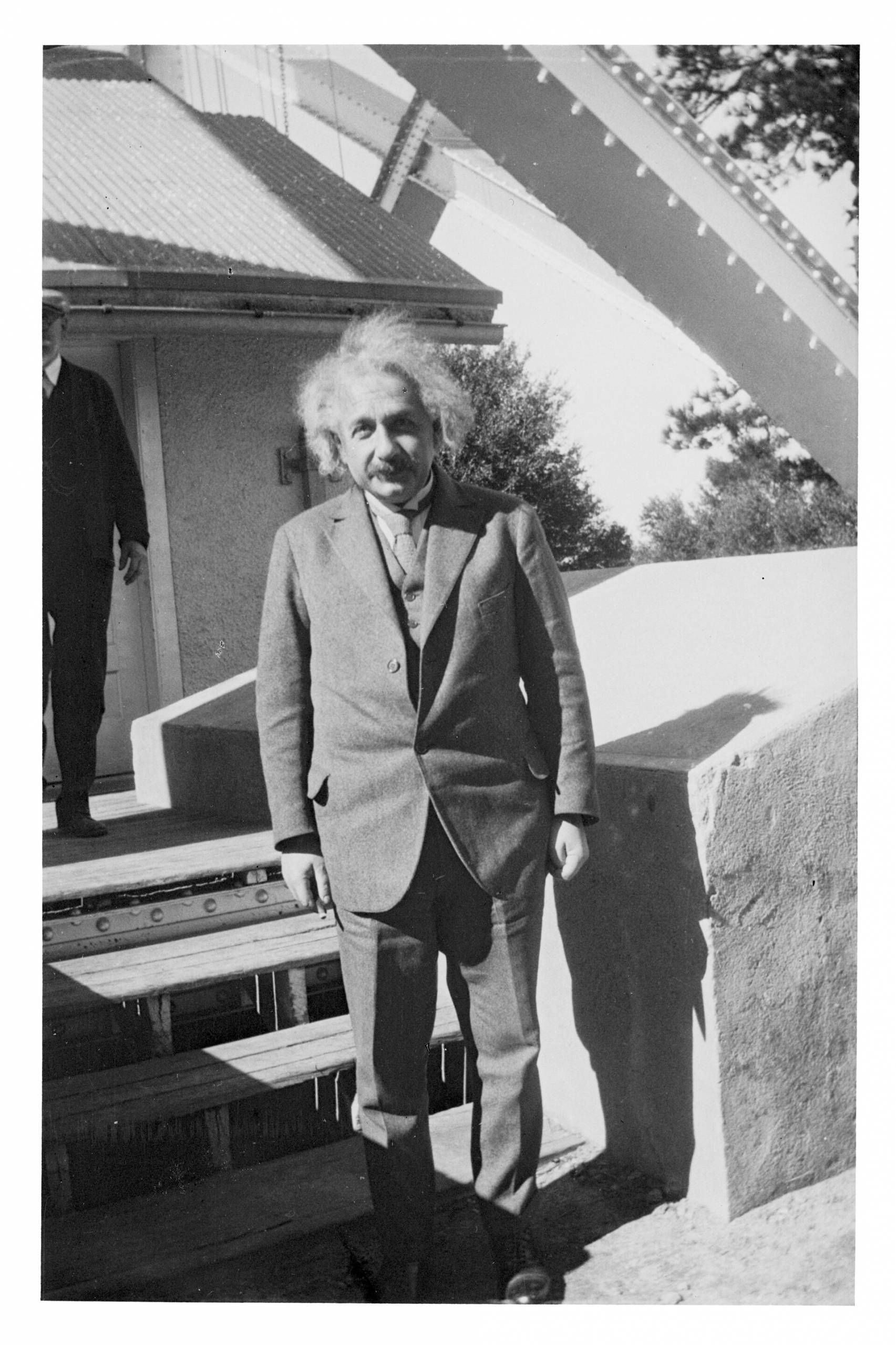 Albert Einstein wears a suit and stands on the steps leading to the Observatory