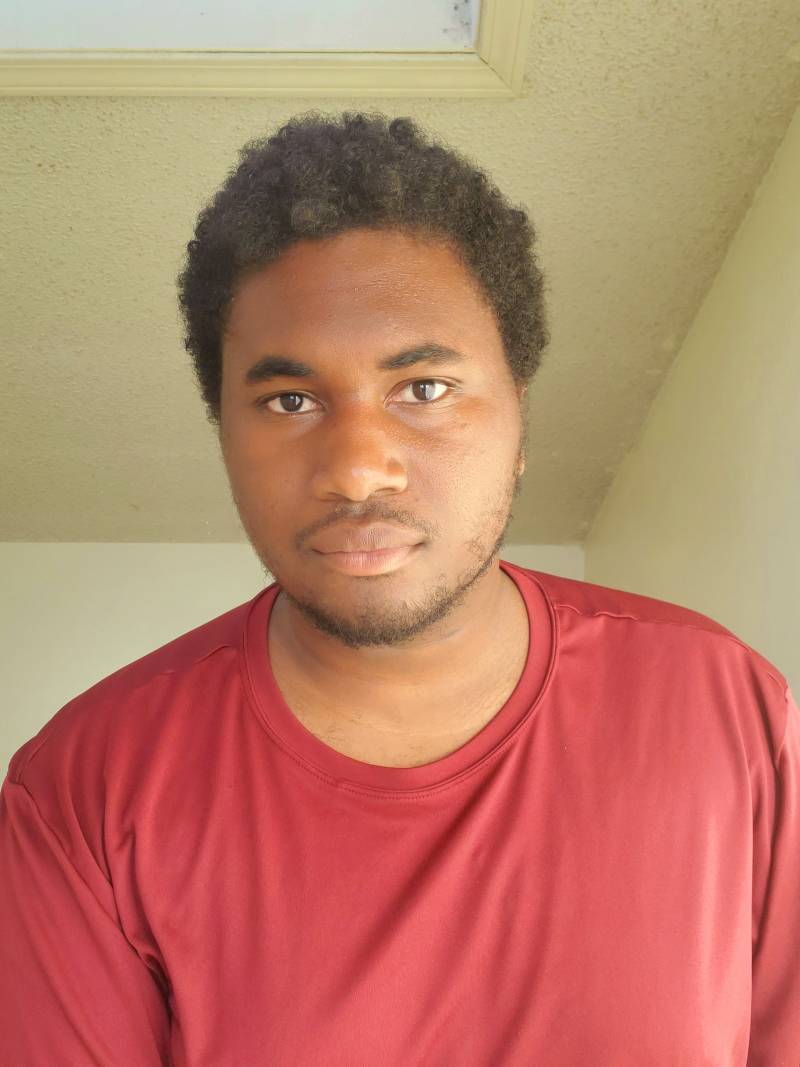 A man with a short afro wearing a red shirt.