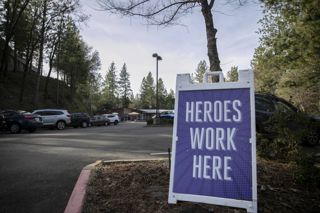 A sign in front of a parking lot that says "HEROES WORK HERE."