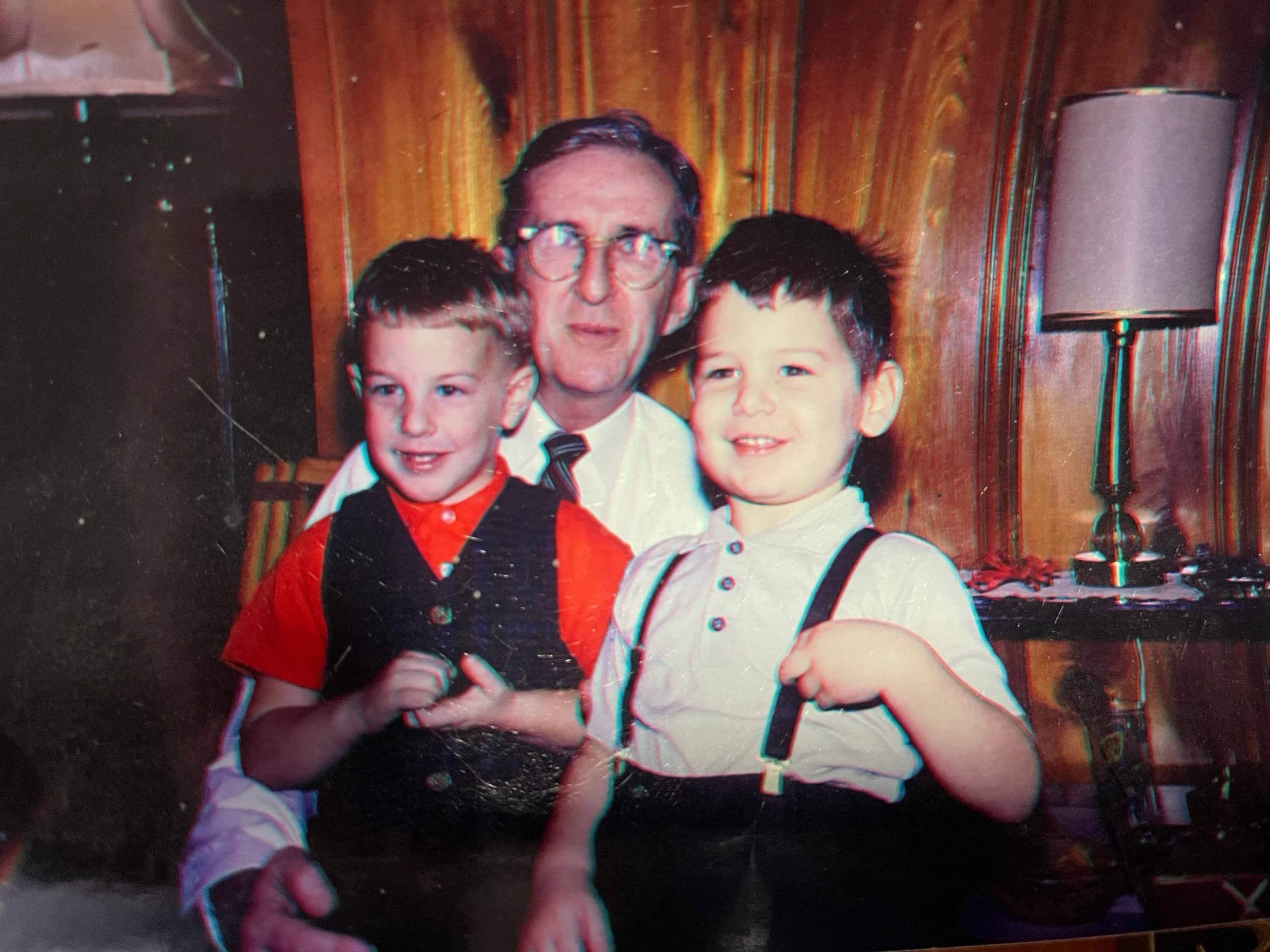 Two little boys sitting on the lap of their grandfather.