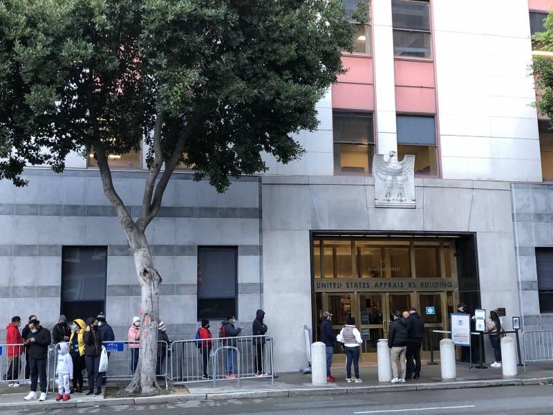 People stand in line outside of a court buidling.