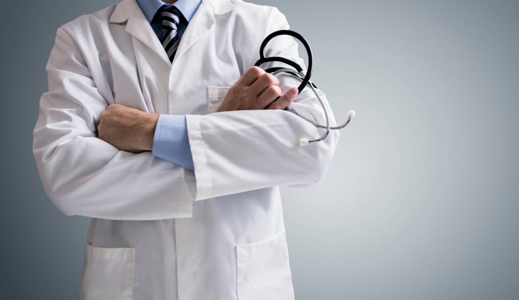 generic photo of person wearing white doctors coat, standing with arms firmly crossed holding stethoscope