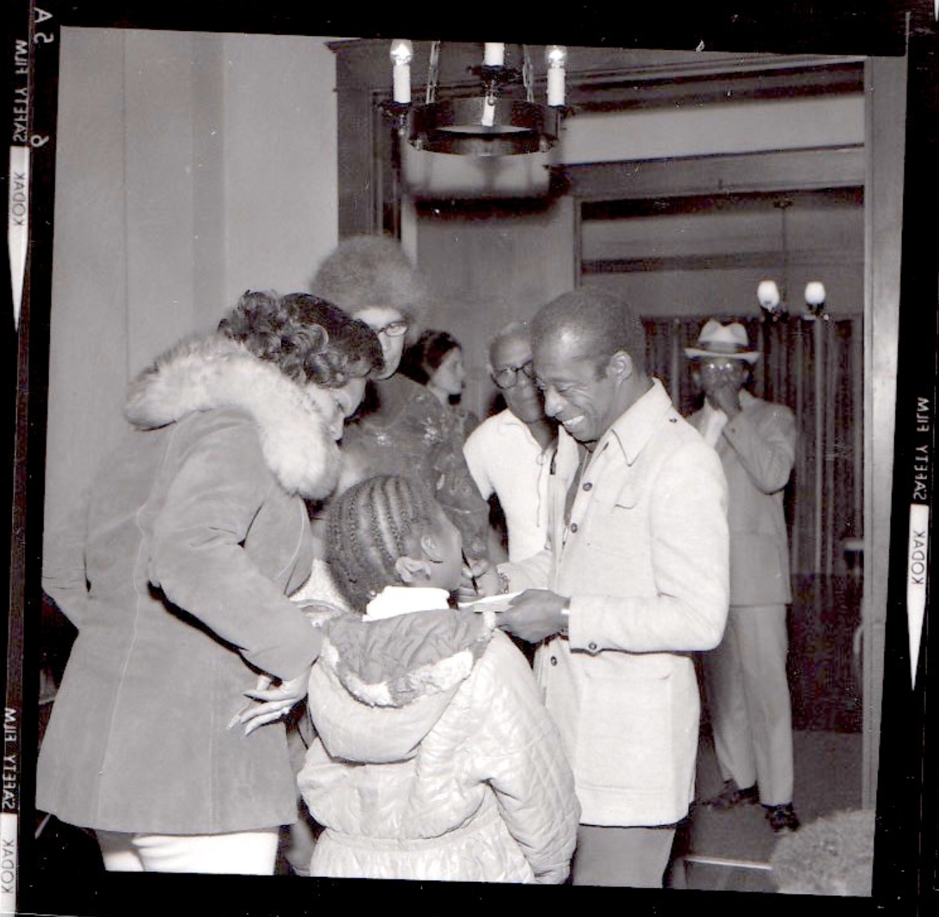Author James Baldwin greet a young child and mother at the door.