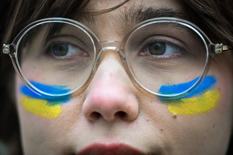 A close up photo of a person wearing glasses with blue and yellow stripes symbolizing the Ukranian flag under their eyes.