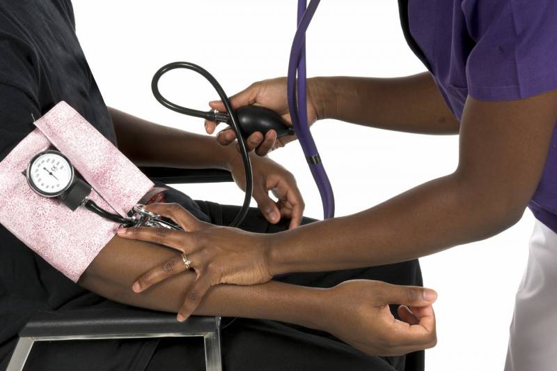 A hand hold a blood pressure pump and a person's arm.