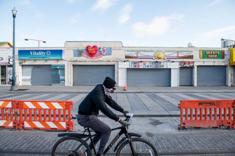 A bicyclist rides past closed shops in Fisherman's Wharf on April 20, 2020.