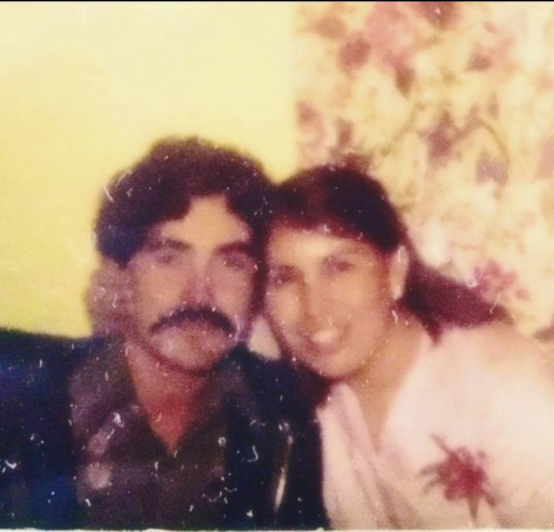 An old, damaged photo of a man and a woman close together.