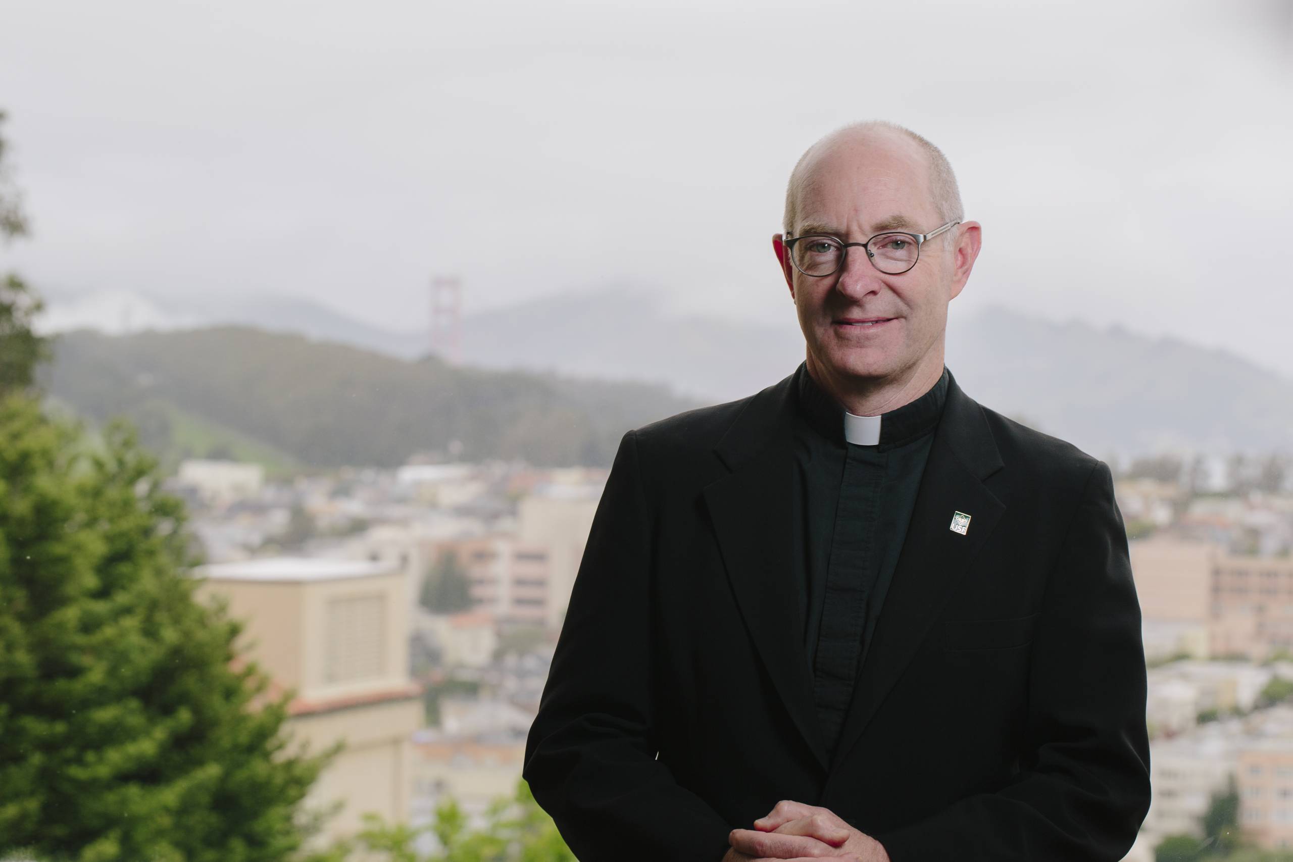 profile of Jesuit reverend with cityscape in background