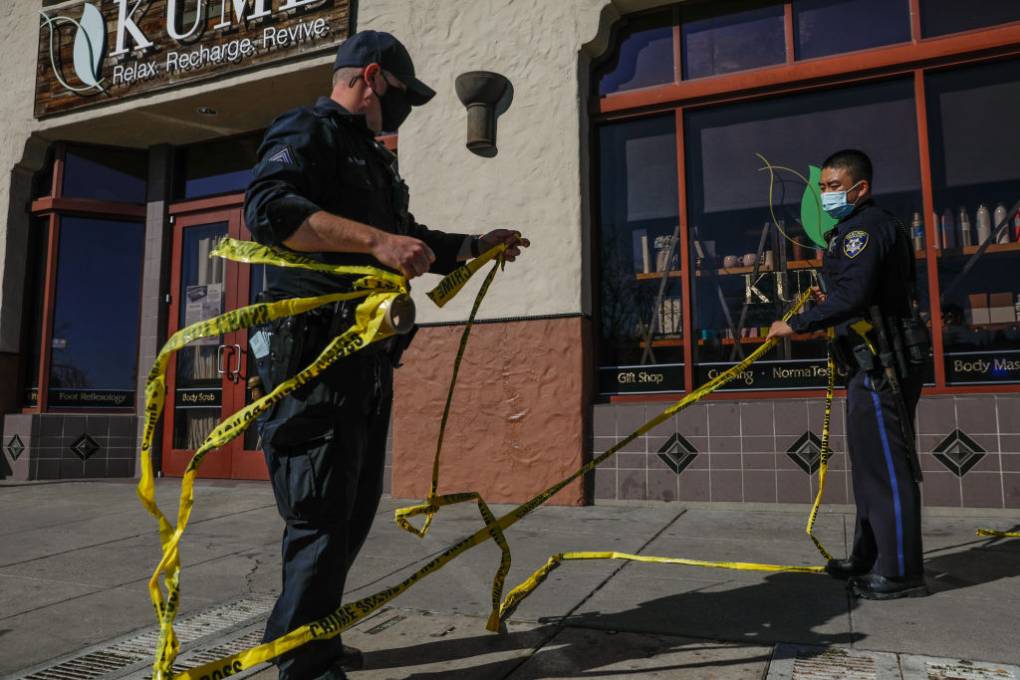 Police officers put up yellow caution tape outside a spa.