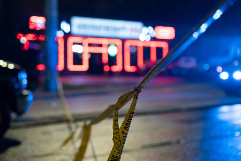 spa building in distance, out of focus, lit by pink neon lights, police tape in foreground