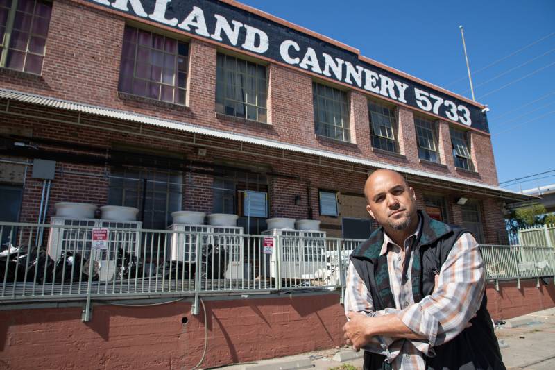 Alistair Monroe posing outside the red-brick Cannery building in East Oakland.