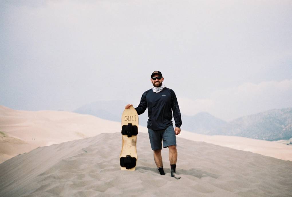 A man stands on a mountainside with a board.