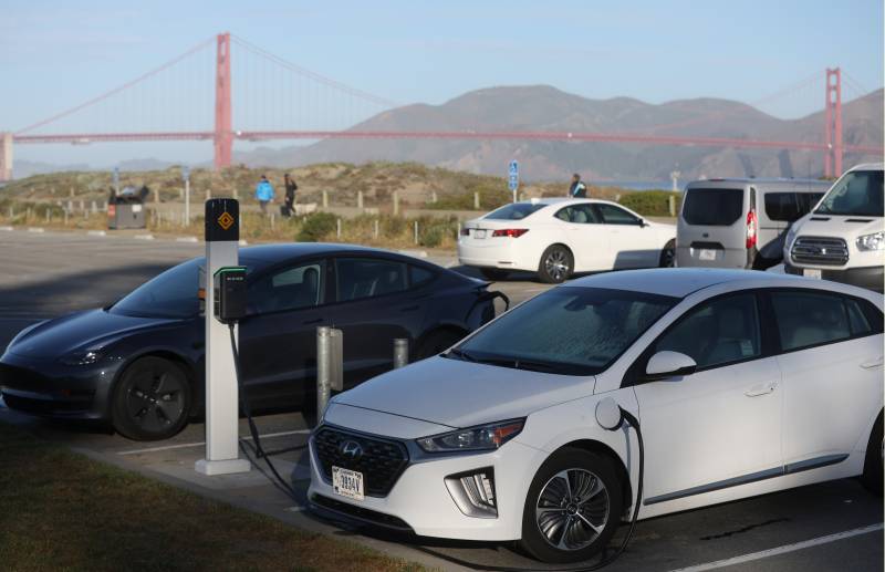 Electric vehicles charging up in an outdoor SF lot, with the Golden Gate Bridge in the background.