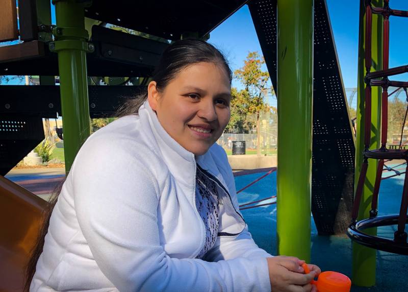 Deisy Ramirez sits at a playground.