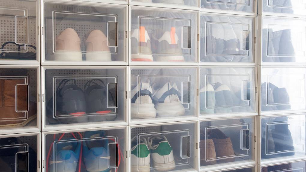 A floor to ceiling shelf displays row after row of sneakers, neatly placed inside clear plastic display boxes.