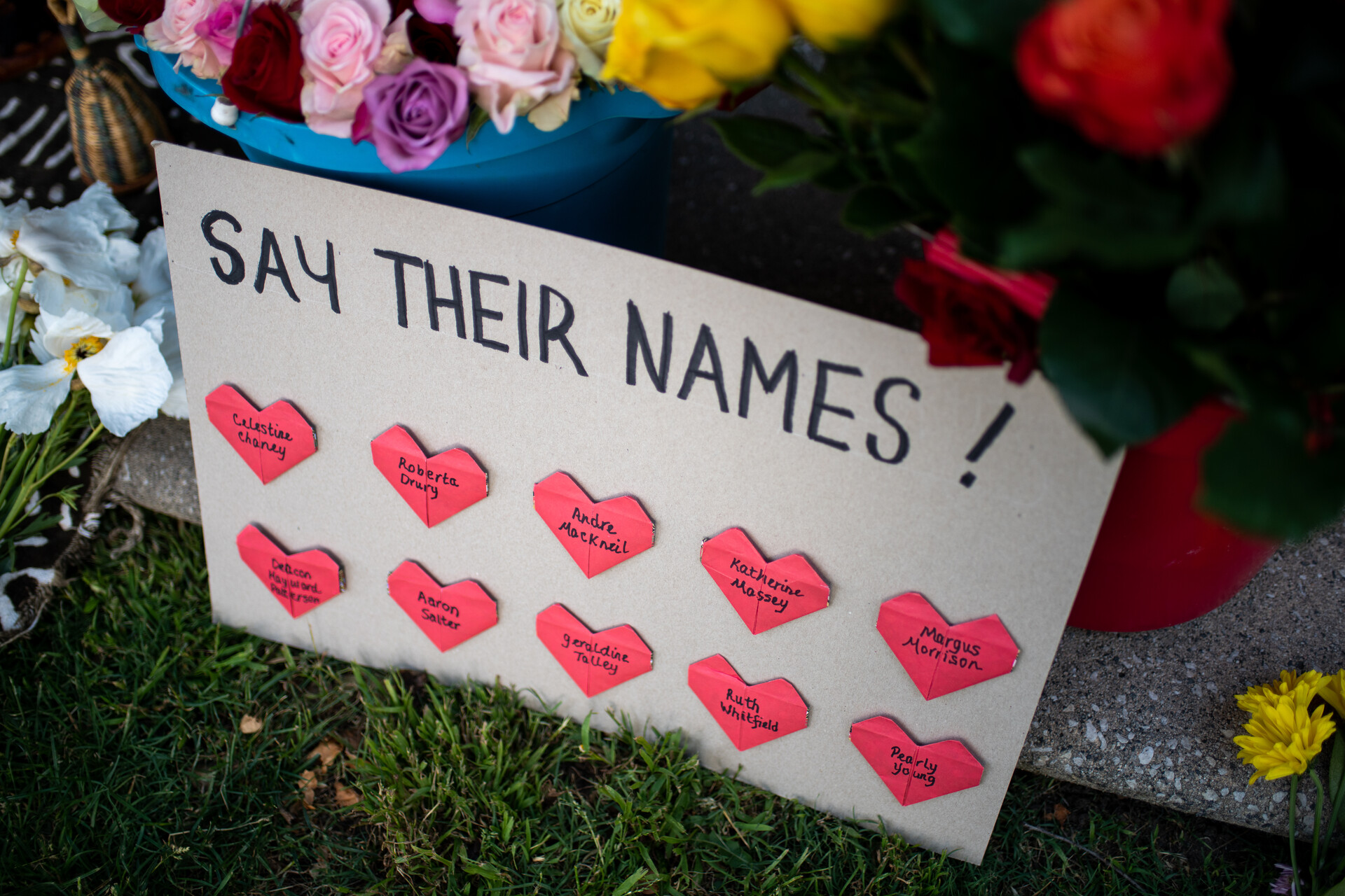 sign reading 'say their names' has pink hearts with names of shooting victims listed