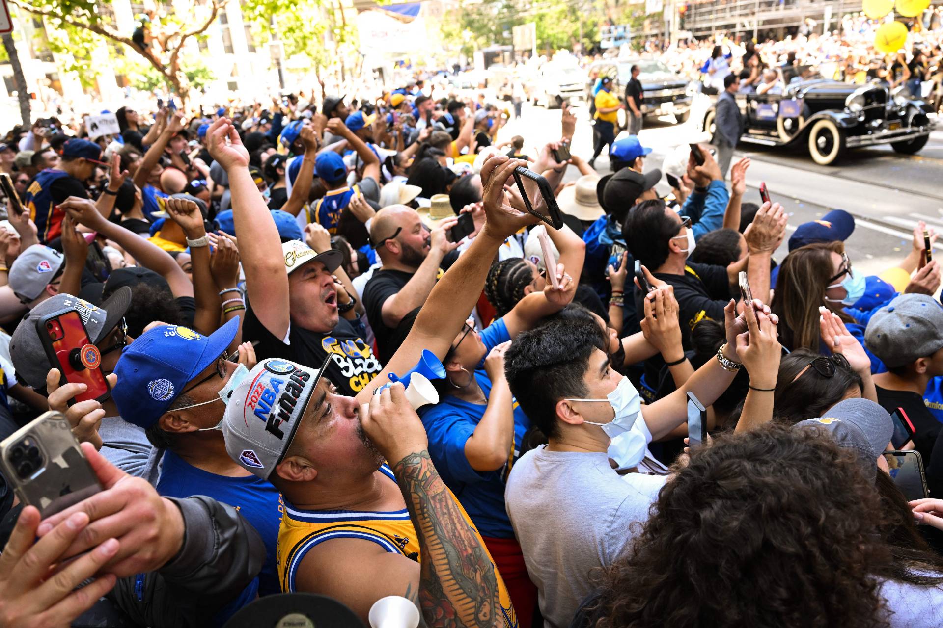 A large crowd of people cheering at the Warriors parade.