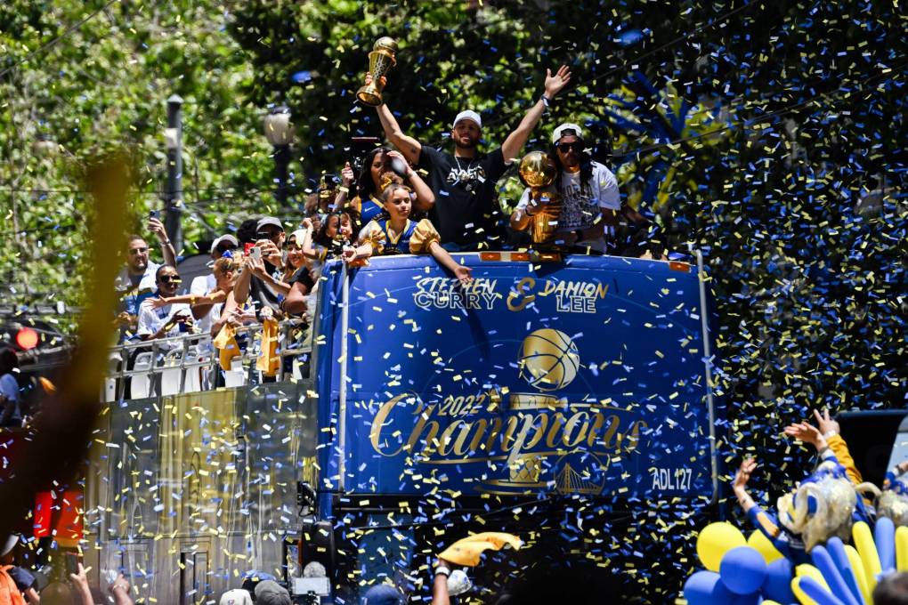 Warriors players on top of a float as they wave to the crowd amidst confetti