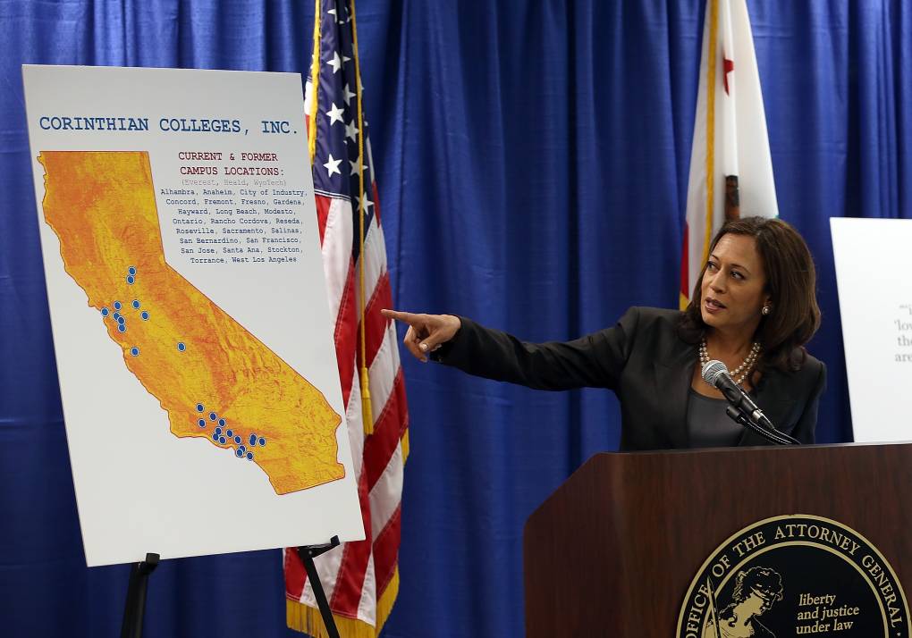 A woman dressed in a black business suit behind a podium points to a map of California.