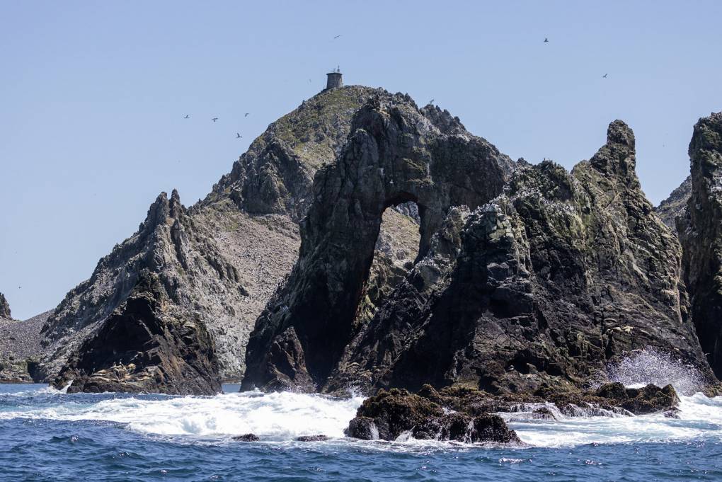 A large, rocky island, with waves crashing around it.