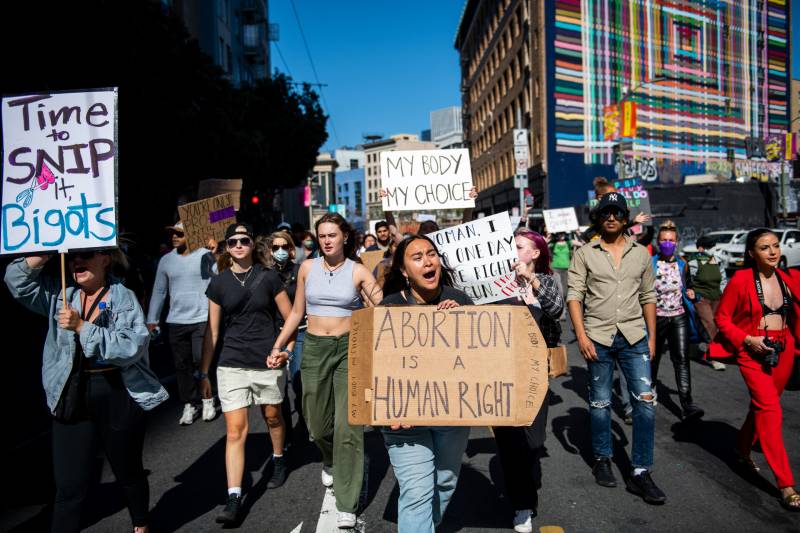 Pro-choice demonstrators holding signs supporting abortion access march on the streets in downtown San Francisco. One woman holds a sign that says, 'Abortion is a human right."